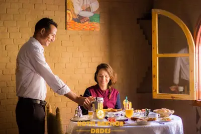 a man and a woman at a table with food at Hotel Babylon Dades in Imdiazene