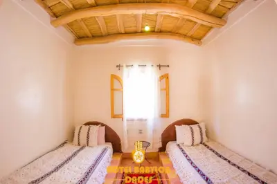 two beds in a room with a wooden ceiling at Hotel Babylon Dades in Imdiazene