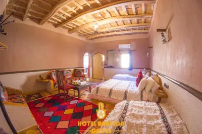 a bedroom with a bed and a table and chairs at Hotel Babylon Dades in Imdiazene