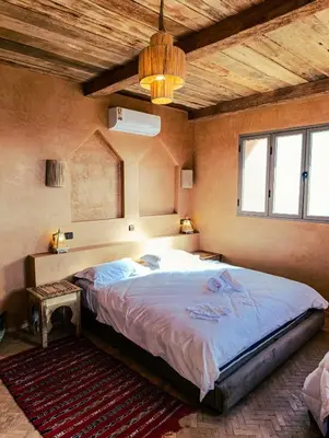 a bedroom with a large bed with a wooden ceiling at Hotel Kasbah Riad Amnir in Mhamid