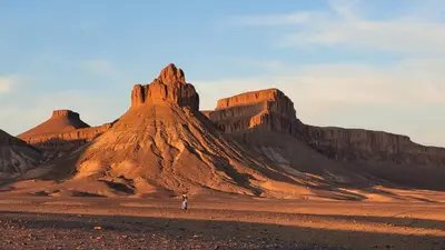 a person standing in the desert near a mountain at Hotel Kasbah Riad Amnir in Mhamid
