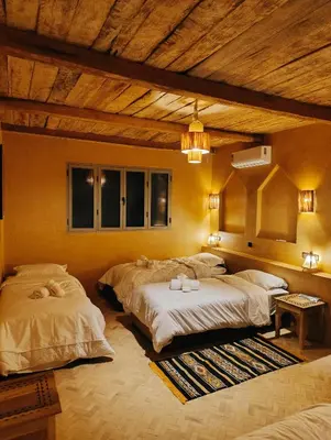 a bedroom with two beds and a wooden ceiling at Hotel Kasbah Riad Amnir in Mhamid