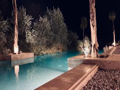 a swimming pool at night with trees and lights at CASA ULIVO villa en pleine nature in Dar Caïd Bou Driss