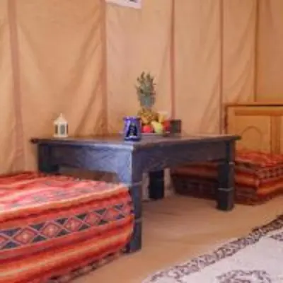 a room with a wooden table and two beds at hagra luxury camp Merzouga in Merzouga