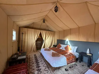 a bedroom with a large bed in a tent at hagra luxury camp Merzouga in Merzouga