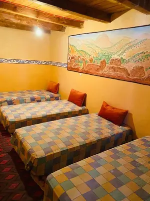 three beds in a room with a painting on the wall at Youssef Rezki Taghia in Taghia