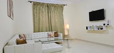 a living room with a white couch and a television at Diar Kamiliya Meknès in Meknès
