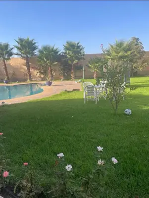a table and chairs in the grass next to a pool at Luxury Villa With Large Private Pool in Marrakech
