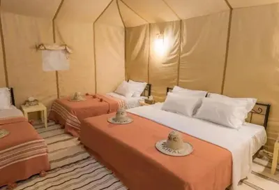 a bedroom with two beds in a tent at Merzouga Sara Luxury Camp in Merzouga