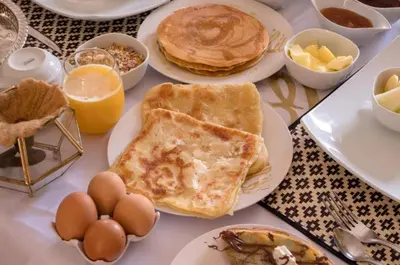 a table topped with plates of pancakes and eggs at Merzouga Sara Luxury Camp in Merzouga