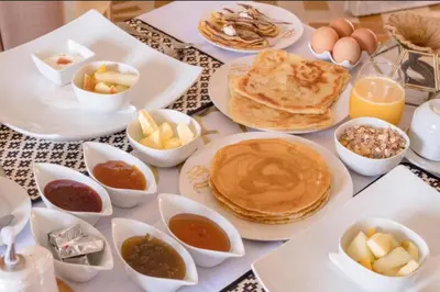 a table topped with pancakes and other breakfast foods at Merzouga Sara Luxury Camp in Merzouga