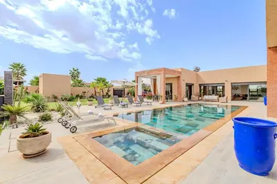 a large swimming pool with chairs and a building at villa Zina, Élégance et luxe,piscine & jacuzzi in Marrakech