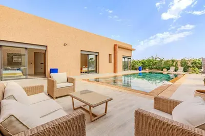 a patio with a pool and chairs and a house at villa Zina, Élégance et luxe,piscine & jacuzzi in Marrakech