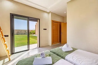 a bedroom with two beds and a large window at villa Zina, Élégance et luxe,piscine & jacuzzi in Marrakech