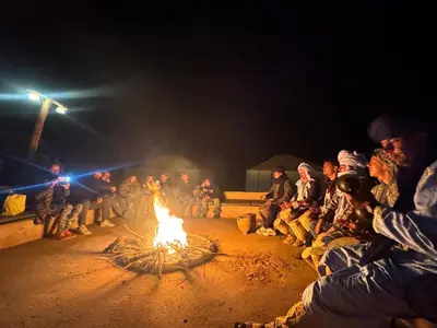 a group of people sitting around a fire at Ksar Merzouga in Merzouga
