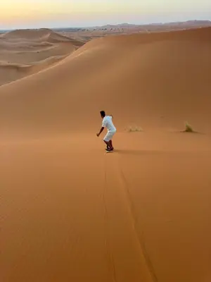 a man walking on the sand in the desert at Ksar Merzouga in Merzouga