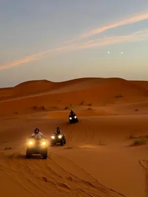two people on atvs driving through the desert at Ksar Merzouga in Merzouga