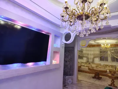 a large flat screen tv in a room with a chandelier at Modern suite BJ in Boujad