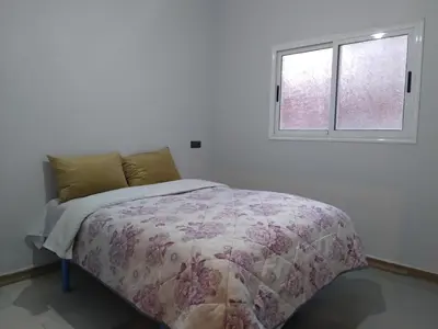 a bed in a white room with a window at Appartement Chez issmail in Tinerhir