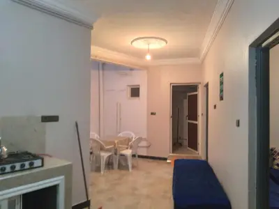 a living room with a fireplace and a table and chairs at Appartement Chez issmail in Tinerhir
