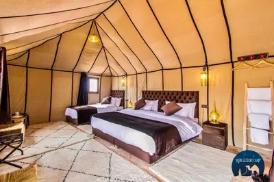 a bedroom with two beds in a tent at Une Nuit de Rêve dans une Tente de Luxe - Expérience en plein désert ! in Merzouga