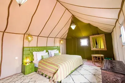a bedroom with a bed in a tent at Une Nuit de Rêve dans une Tente de Luxe - Expérience en plein désert ! in Merzouga