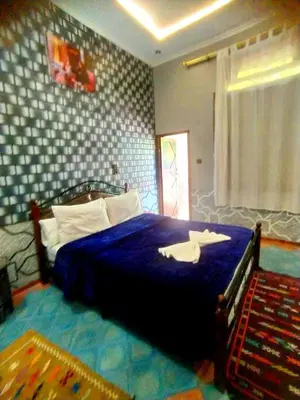a bedroom with a bed with a blue comforter at Hôtel La Vallée Des Oiseaux in Boumalne