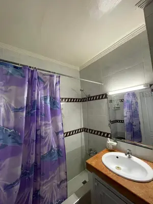 a bathroom with a sink and a purple shower curtain at chamber chez l habitant pour les femmes à côté CTM & Gare du train in Fès