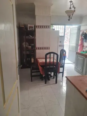 a kitchen with a table and chairs and a refrigerator at chamber chez l habitant pour les femmes à côté CTM & Gare du train in Fès