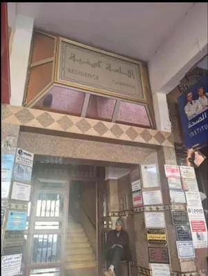 a man sitting on a chair in front of a building at chamber chez l habitant pour les femmes à côté CTM & Gare du train in Fès