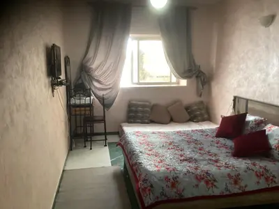 a bedroom with a bed with red pillows and a window at chamber chez l habitant pour les femmes à côté CTM & Gare du train in Fès