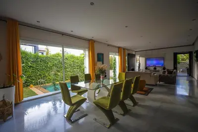 a dining room with a glass table and green chairs at Villa familiale moderne avec piscine in Fès