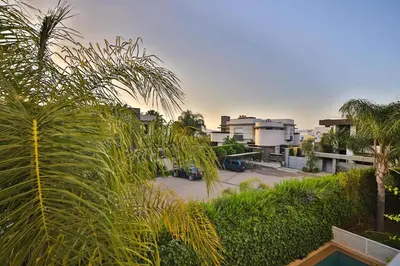 a view of a parking lot with palm trees and buildings at Villa familiale moderne avec piscine in Fès