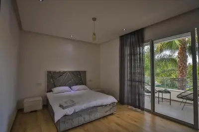 a bedroom with a large bed and a balcony at Villa familiale moderne avec piscine in Fès