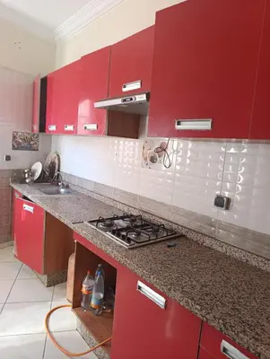 a kitchen with red cabinets and a stove top oven at Ramz Appartement in Beni Mellal