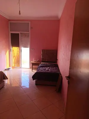 a bedroom with a bed in a red wall at Ramz Appartement in Beni Mellal
