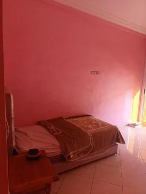 a bed in a room with a red wall at Ramz Appartement in Beni Mellal