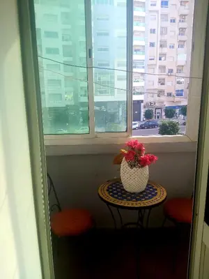 a table with a vase with flowers on it in a window at Air house in Gare de Meknès
