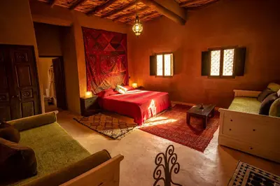 a bedroom with a red bed and a couch at Dar Kamar in Ouarzazate