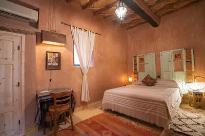 a bedroom with a bed and a desk and a window at Dar Kamar in Ouarzazate
