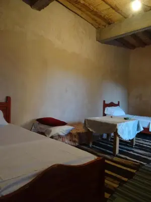a room with two beds and a table in it at Ryad-IGRANE in Ouarzazate