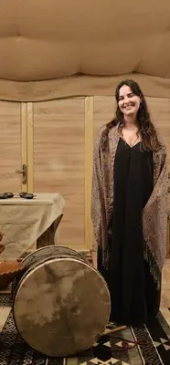 a woman is standing next to a drum at Royal Sahara Dome Camp in Merzouga