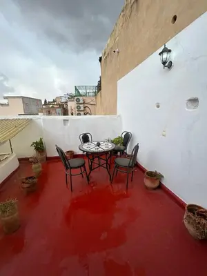 a patio with a table and chairs on a red floor at DarMouniaFès in Fès