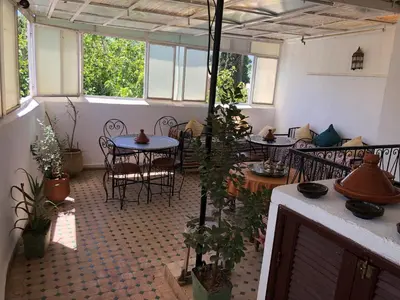 an empty room with tables and chairs and plants at Dar Lalla Wafae in Fès