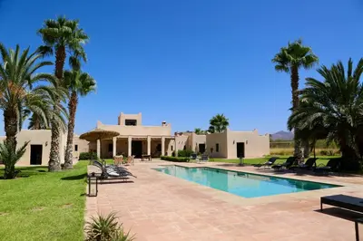 a villa with a swimming pool and palm trees at Villa Beldi Chic Novari avec piscine chauffée - 8 personnes - Marrakech - Petit déjeuner inclus in Douarbel Kial