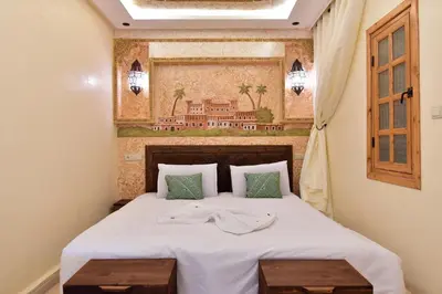 a bedroom with a bed with two wooden tables at Dar Chams Ouarzazate in Ouarzazate