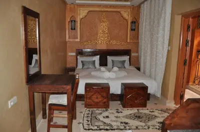 a bedroom with a bed with a table and a desk at Dar Chams Ouarzazate in Ouarzazate