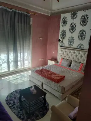 a bedroom with a bed and a chair and a table at Chez Adam in Meknès