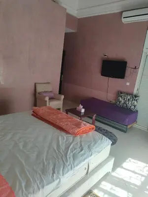 a bedroom with a bed and a couch and a tv at Chez Adam in Meknès