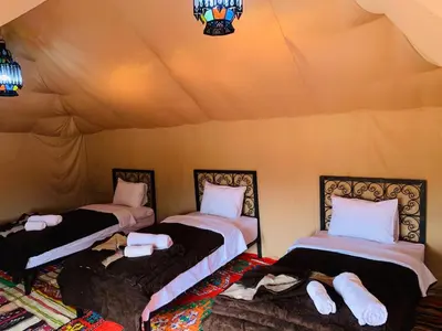 a room with three beds in a tent at Eco Merzouga luxury camp in Merzouga